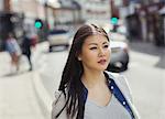 Serious, pensive young woman walking on urban street