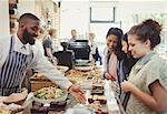 Male worker helping female customers in cafe