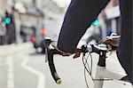 Hands on man on bicycle handlebars, commuting on sunny urban street