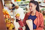 Woman shopping, examining apple in grocery store