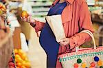 Pregnant woman shopping for apples in grocery store