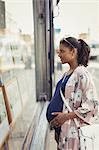 Pregnant woman browsing real estate listings at storefront