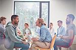 Group watching man and woman talking face to face in group therapy session