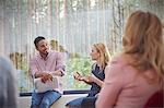 Male therapist listening to talking woman in group therapy session