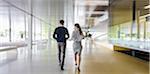 Businessman and businesswoman walking in modern office corridor