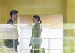 Businessman and businesswoman talking in modern office corridor