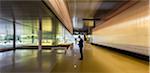 Businessman texting with smart phone in illuminated modern office lobby corridor