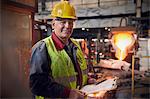 Portrait confident steelworker supervisor with clipboard in steel mill