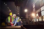 Steelworkers using laptop in steel mill