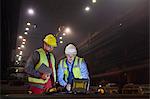 Steelworkers using laptop in dark steel mill