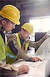 Engineer and steelworker discussing blueprints in steel mill