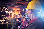 Steelworker talking, using walkie-talkie in steel mill