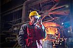 Steelworker talking, using walkie-talkie in steel mill