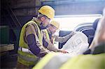 Engineer and steelworker examining blueprints in steel mill