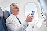 Businessman listening to music with headphones and mp3 player on airplane
