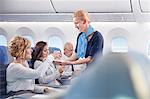 Flight attendant serving drink to woman on airplane