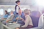 Mature couple toasting champagne glasses in first class on airplane