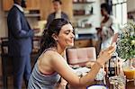 Young woman texting with smart phone at breakfast table