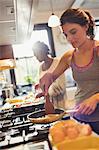 Woman cooking eggs on stove in kitchen