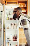 Young man peering into refrigerator