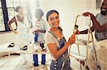 Portrait smiling, confident woman painting living room with friends