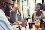 Young man texting with smart phone at kitchen table