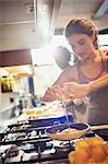 Young woman cracking egg over skillet on stove in kitchen