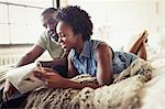 Couple relaxing, reading newspaper on bed