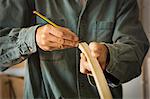 A craftsman using a pencil and marking a piece of curved wood.