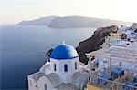 Evening view over the Caldera from Oia with blue domed church and distant volcanic cliffs, Santorini, Greek Islands, Greece, Europe