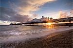 Brighton Pier at sunset with dramatic sky and waves washing up the beach, Brighton, East Sussex, England, United Kingdom, Europe