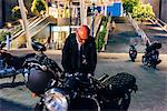 Mature businessman outdoors at night, preparing to ride motorcycle