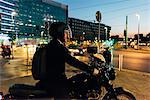 Mature businessman outdoors at night, riding motorcycle