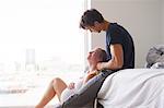 Man sitting on bed gazing at pregnant girlfriend