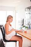 Pregnant young woman at desk looking at smartphone