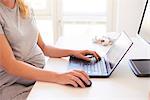 Cropped shot of pregnant young woman at desk typing on laptop