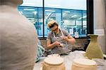 Woman in art studio glazing pottery