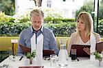 Couple al fresco dining at restaurant, selecting from menu