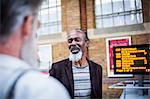 Three mature men at train station