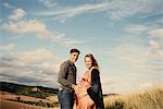 Portrait of pregnant mid adult couple on rural hillside