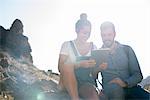 Young hiking couple looking at digital tablet in sunlit valley, Las Palmas, Canary Islands, Spain