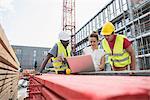 Architect using laptop with construction worker at building site