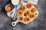 Freshly baked pumpkin muffins with pumpkin seeds and pecans on a cutting board.