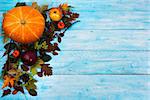 Happy Thanksgiving  greeting with pumpkin, apples and autumn leaves on the left side of blue wooden table. Fall background with seasonal vegetables and fruits, copy space