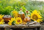 Natural Homemade sunflower oil with flowers and seeds on old table. Outdoors