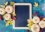 White pumpkins and fall leaves. Autumn background with festive decoration and vintage chalkboard for your message.
