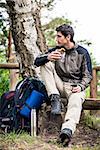 Hiker taking food break with tea and sandwich in shade of tree