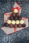 Chocolate pralines shape Christmas tree on black stone table top view with coconut snowflakes