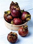 Heap of Fresh Ripe Mangosteen in Wooden Bowl closeup on Light Blue Wooden background