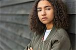 Beautiful mixed race African American girl teenager female young woman outside wearing a green bomber jacket looking sad depressed or thoughtful